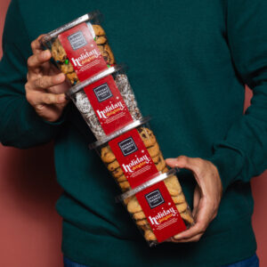 Image of man holding Corner Bakery cookie containers